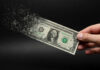 Dollar bill disintegrating while held by hand