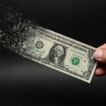 Dollar bill disintegrating while held by hand