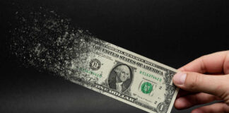 Dollar bill disintegrating while held by hand