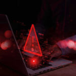Warning symbol over laptop with user