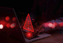 Warning symbol over laptop with user