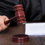 Judges hand holding gavel next to documents