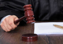 Judges hand holding gavel next to documents