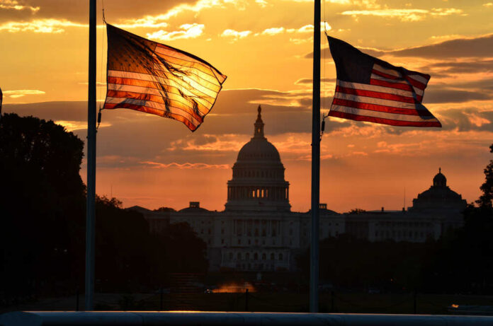 shutterstock_113389501.jpg Silhouetted American flags in front of the Capitol building during sunset
