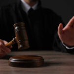 Judge holding gavel, hand raised in courtroom