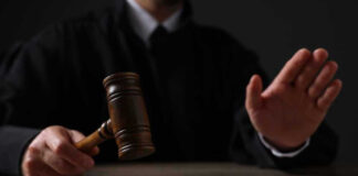 Judge holding gavel, hand raised in courtroom