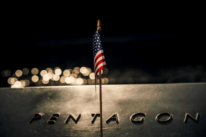 shutterstock_2321355077.jpg American flag above engraved Pentagon sign at night