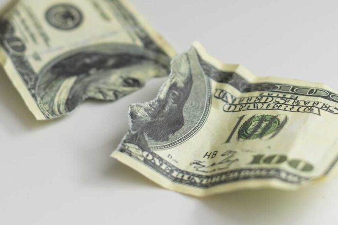 Torn and crumpled hundred dollar bills on a white surface