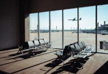 View of an airport waiting area with an airplane taking off in the background