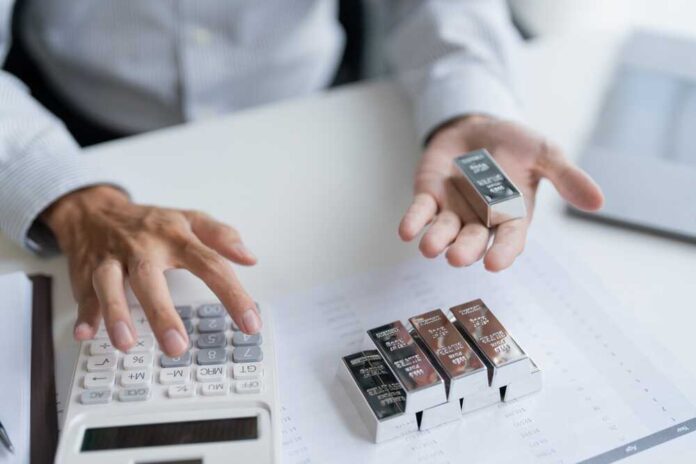 Person analyzing precious metal bars with a calculator