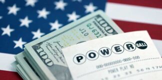 Powerball lottery ticket placed on a stack of cash with an American flag background