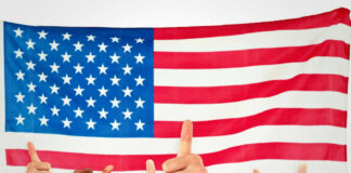 Thumbs up in front of American flag.