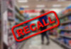 Recall Alert Hits 350K Babies Recall stamp on blurred store aisle background.