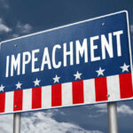 A sign displaying the word 'IMPEACHMENT' against a cloudy sky