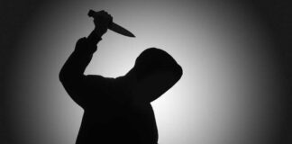 Silhouette of hooded figure holding a knife.