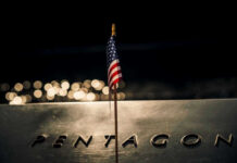 American flag above engraved Pentagon sign at night