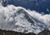 Snow-covered mountain peak partially obscured by clouds