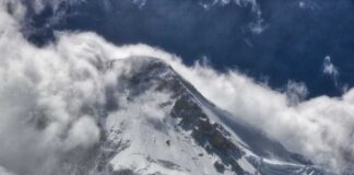 Snow-covered mountain peak partially obscured by clouds