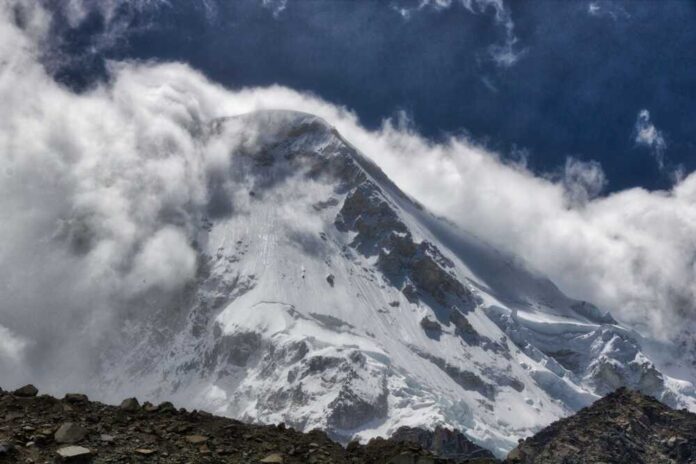 Snow-covered mountain peak partially obscured by clouds