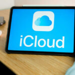 A tablet displaying the iCloud logo on a wooden desk