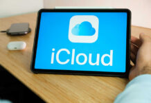 A tablet displaying the iCloud logo on a wooden desk