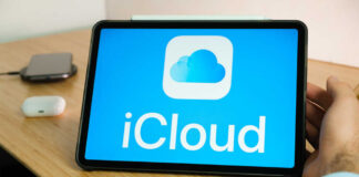 A tablet displaying the iCloud logo on a wooden desk