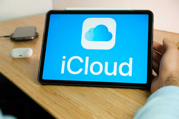 A tablet displaying the iCloud logo on a wooden desk