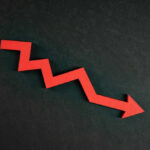 Red zigzag arrow pointing down on dark background.