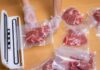 Hands wearing gloves vacuum sealing meat in plastic bags