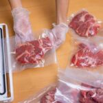 Hands wearing gloves vacuum sealing meat in plastic bags