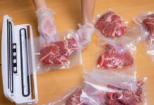 Hands wearing gloves vacuum sealing meat in plastic bags