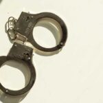A pair of metallic handcuffs resting on a light surface