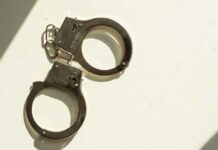 ARRESTED: Classified Documents Sent to Epstein A pair of metallic handcuffs resting on a light surface