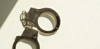 A pair of metallic handcuffs resting on a light surface