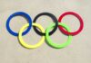 Colorful Olympic rings arranged on sandy surface