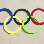 Colorful Olympic rings arranged on sandy surface