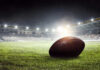 Football on field in illuminated stadium at night.