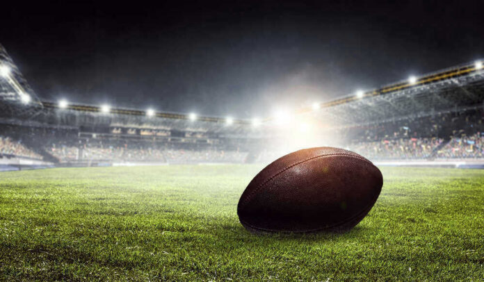 Football on field in illuminated stadium at night.