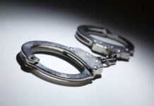 Close-up of metallic handcuffs on a light surface