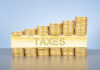 Stacked coins with TAXES on block beneath.