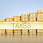 Stacked coins with TAXES on block beneath.