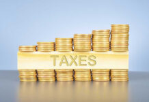 Stacked coins with TAXES on block beneath.