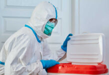 Healthcare worker in protective gear disposing of waste