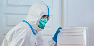 Healthcare worker in protective gear disposing of waste