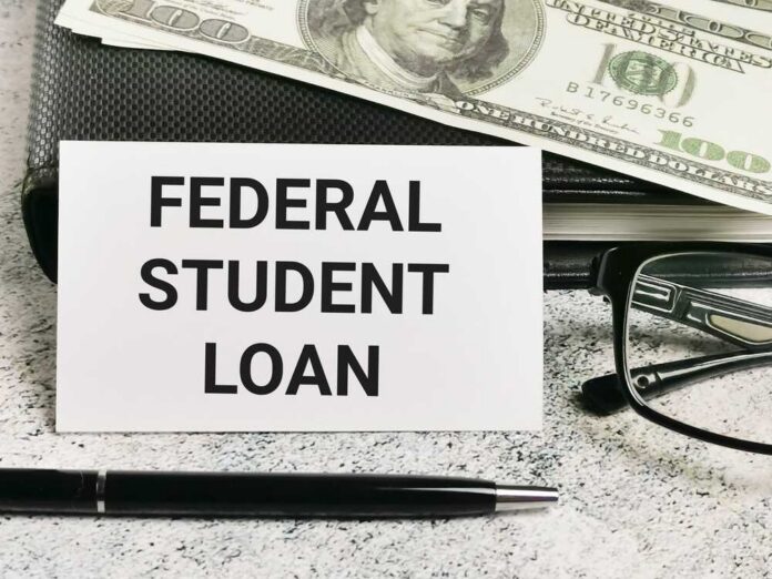 A sign reading 'Federal Student Loan' next to a stack of money and a pen