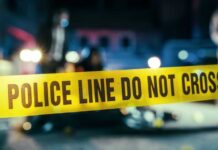 Halfway House Resident Found CHOPPED Up In Pond Police line caution tape at a crime scene with blurred figures in the background