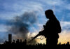CATASTROPHIC Failure Armed Known ISIS Terrorist Silhouetted soldier with rifle, smoky cityscape background.