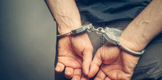 Person with handcuffs behind their back.