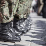 Row of soldiers in black boots and camouflage pants standing in formation