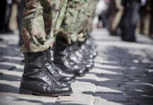 Row of soldiers in black boots and camouflage pants standing in formation